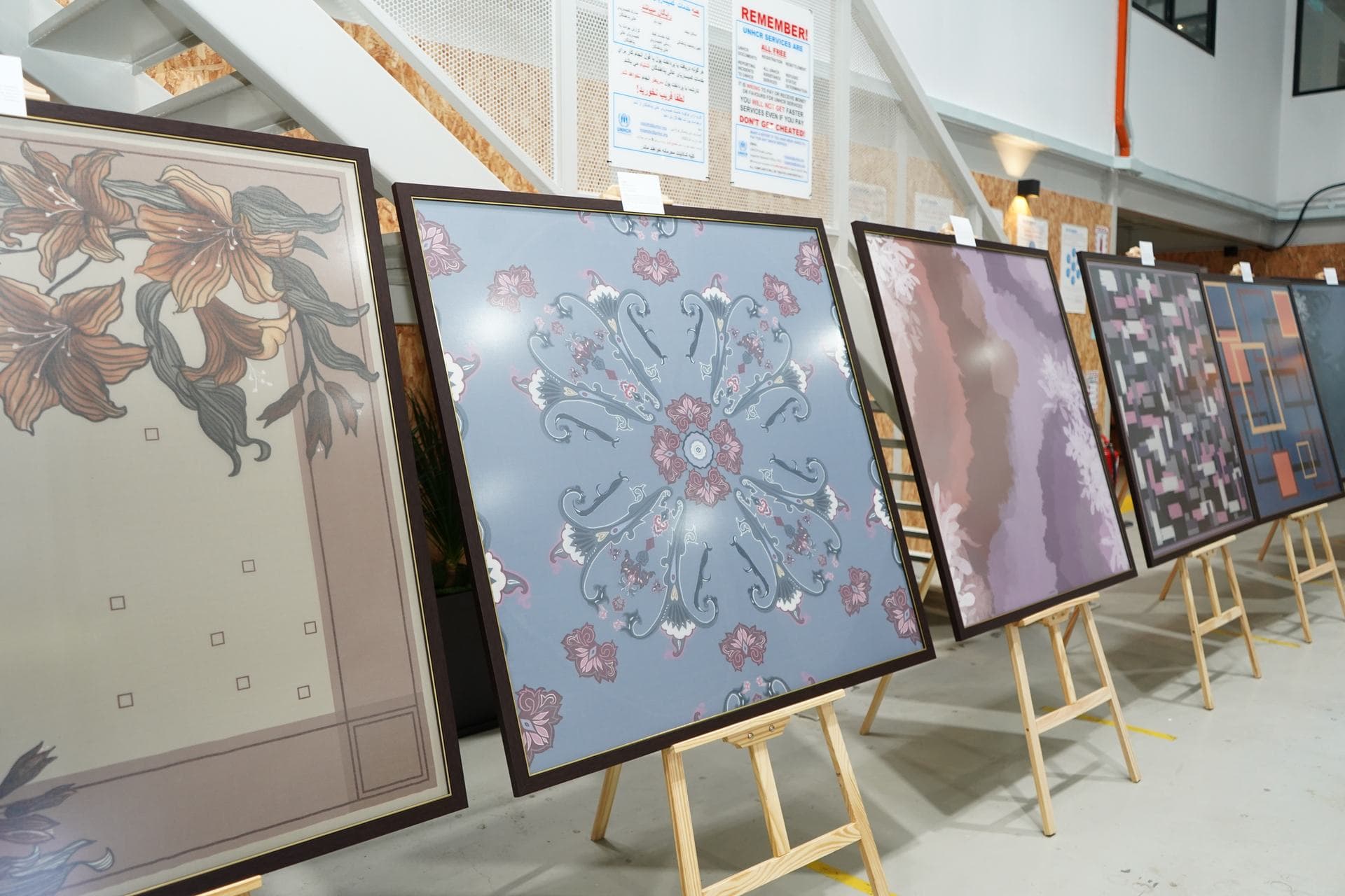 Framed artworks displayed on easels in an exhibition space.